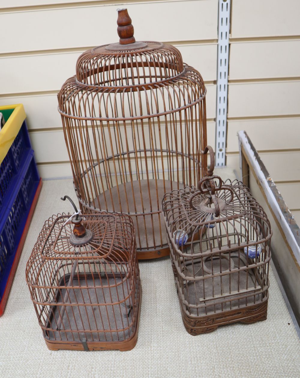 Three vintage Spanish birdcages, made of wood and metal, one with porcelain feeder pots.